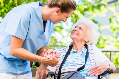 nurse holding hand of senior woman in pension home