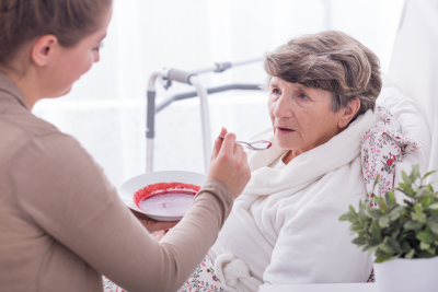 caregiver giving meal to elderly woman